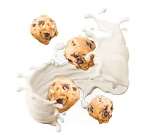 Schokoladenkekse, die durch Milch in der Luft fliegen, mit Spritzern von frischer Milch.